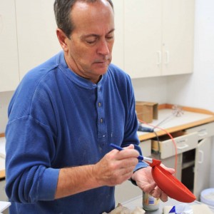 Ceramics student Alan Horton glazes one of his handmade bowls for the event.